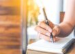hand with pencil writing on a notebook